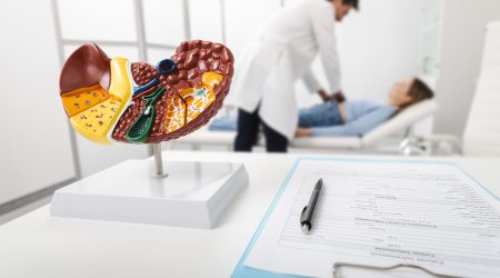 Gastroenterologist palpates painful abdomen of woman, revealing liver disease in doctor's office of medical clinic. Human liver health